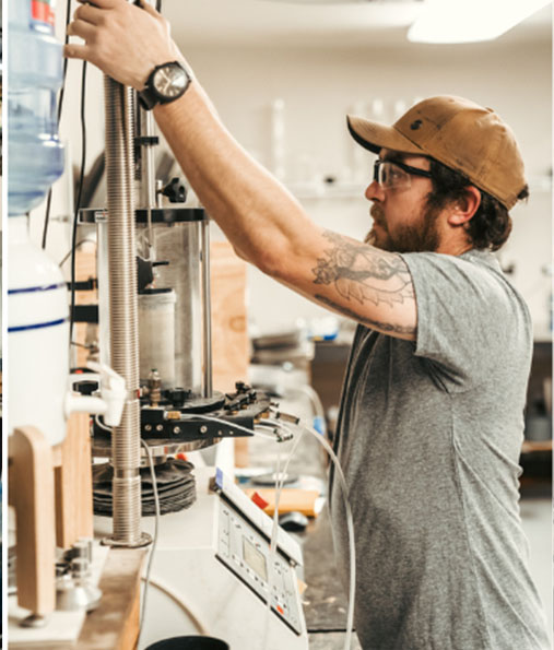 Man adjusting equipment in a Quality Testing LLC laboratory setting.