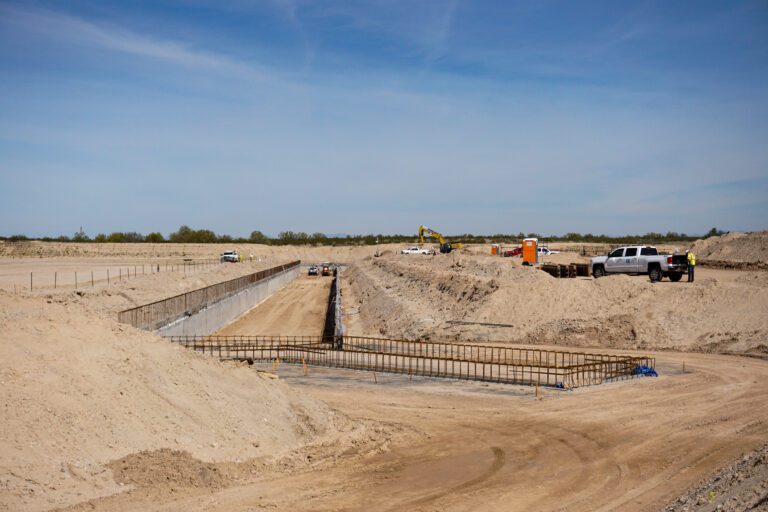 A construction site with ongoing civil engineering services infrastructure development, featuring excavation work and construction machinery under a clear sky.